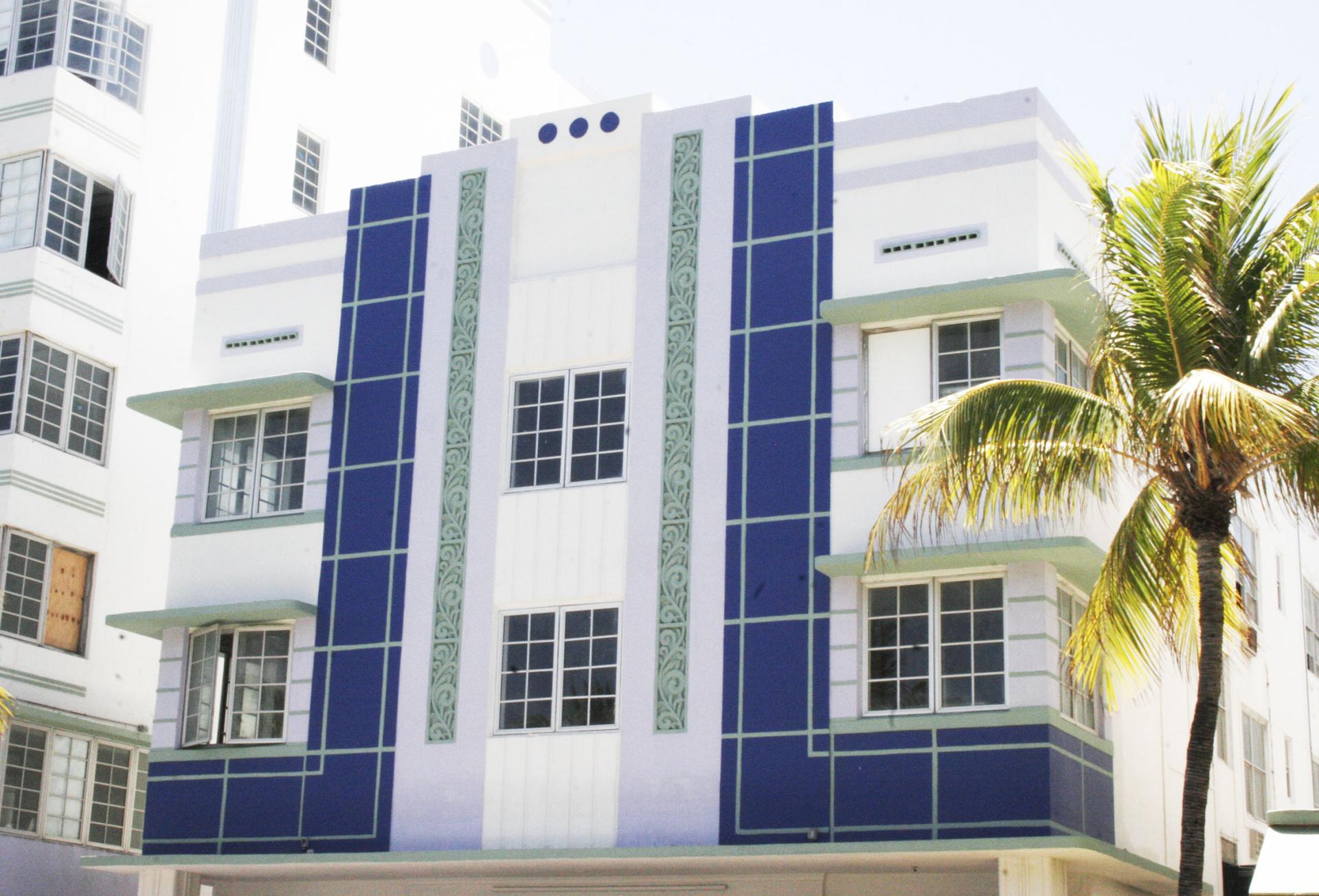 Art Deco building facade in Miami Beach, featuring blue accents and palm trees, highlighting northern seaside town revival.