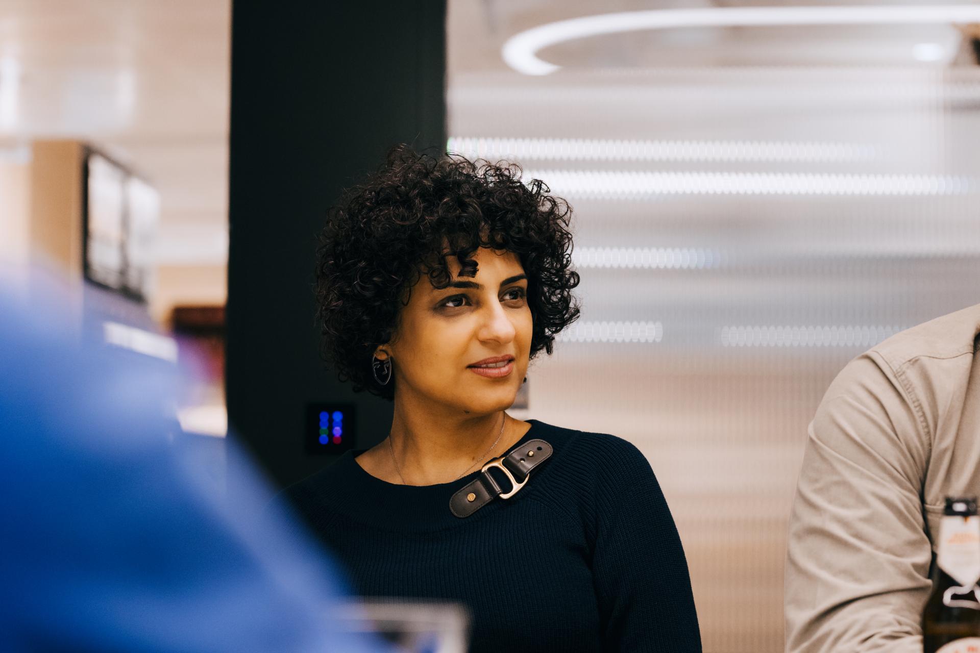 A woman with curly hair listens intently during a roundtable discussion on neurodiversity at Material Source Studio.