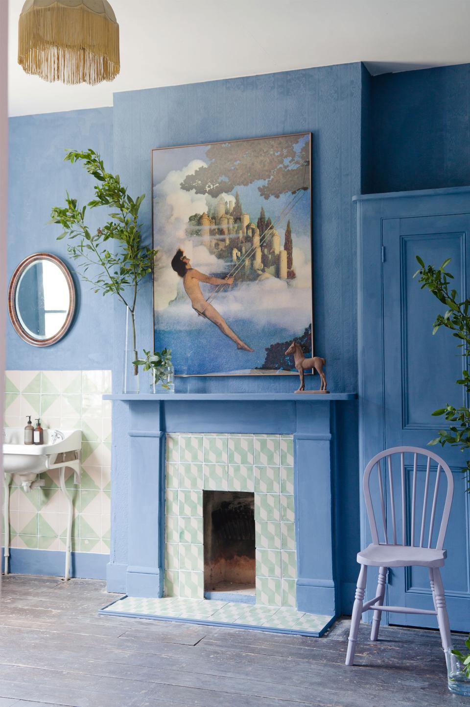 Stylish blue interior featuring a vintage painting, plants, and a unique fireplace, reflecting 2LG Studio's design aesthetic.