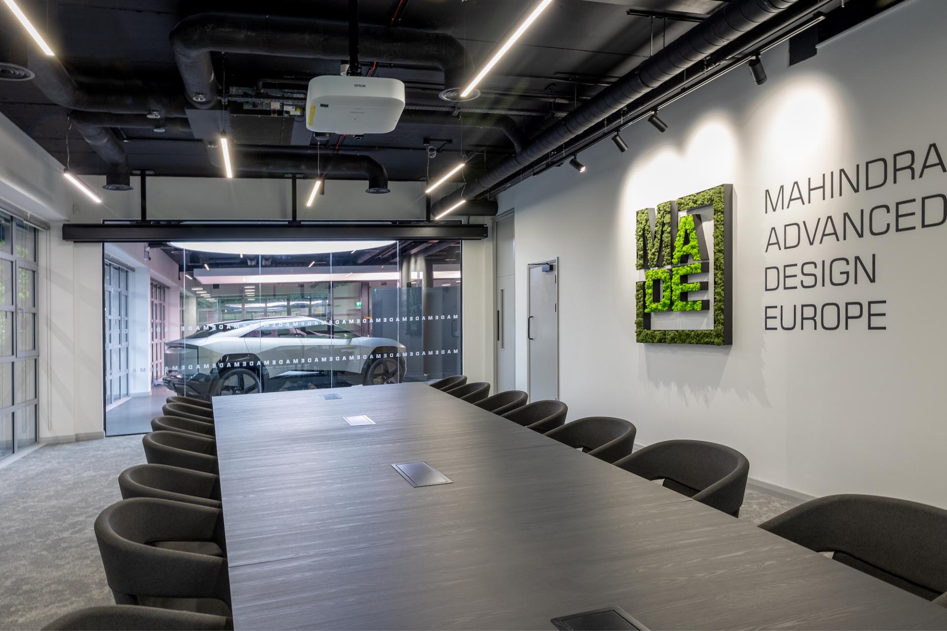 Modern conference room featuring a long table, ergonomic chairs, and a distinctive greenery wall design for M1NT Studio.