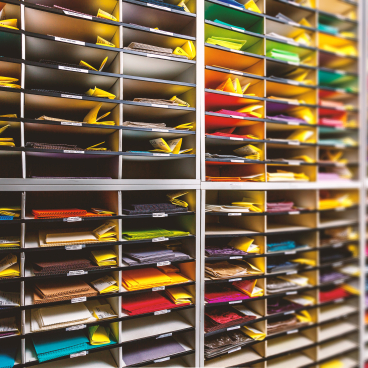 Colorful samples of performance upholstery fabrics organized in shelves, showcasing Agua's textile design and innovation.