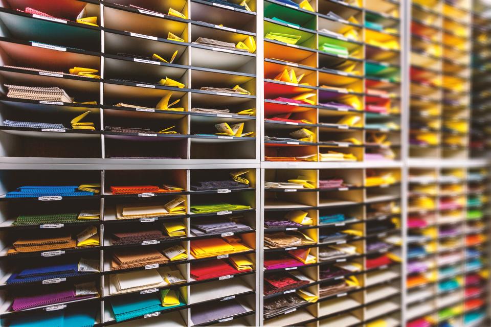 Colorful samples of performance upholstery fabrics organized in shelves, showcasing Agua's textile design and innovation.