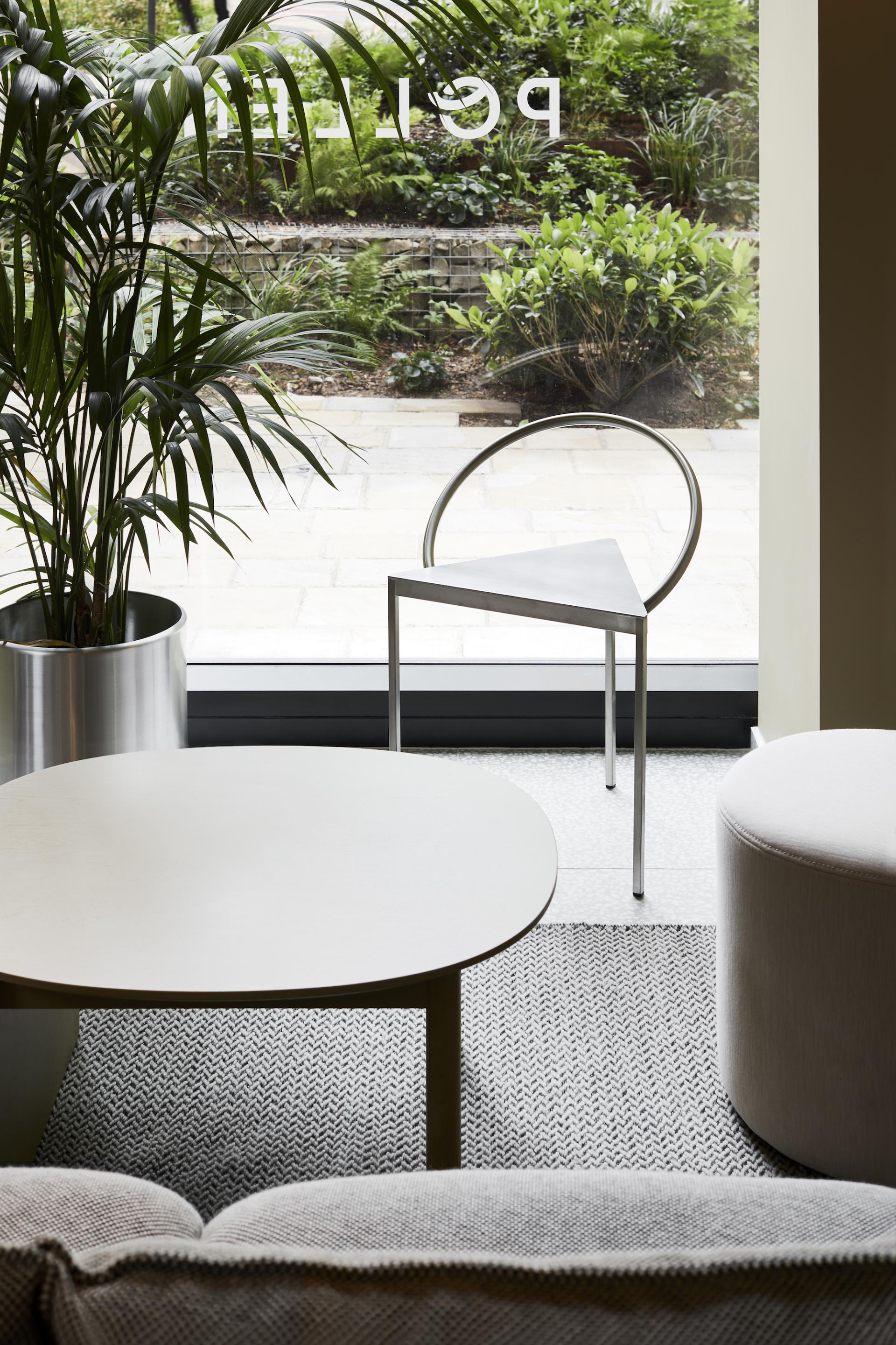 Modern café interior featuring a sleek metal chair, plants, and minimalistic furniture highlighting Pollen Bakery's design ethos.