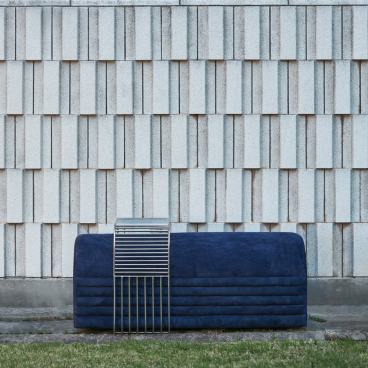 Modernist-inspired blue bench against a textured concrete wall, showcasing contemporary Uruguayan design elements.