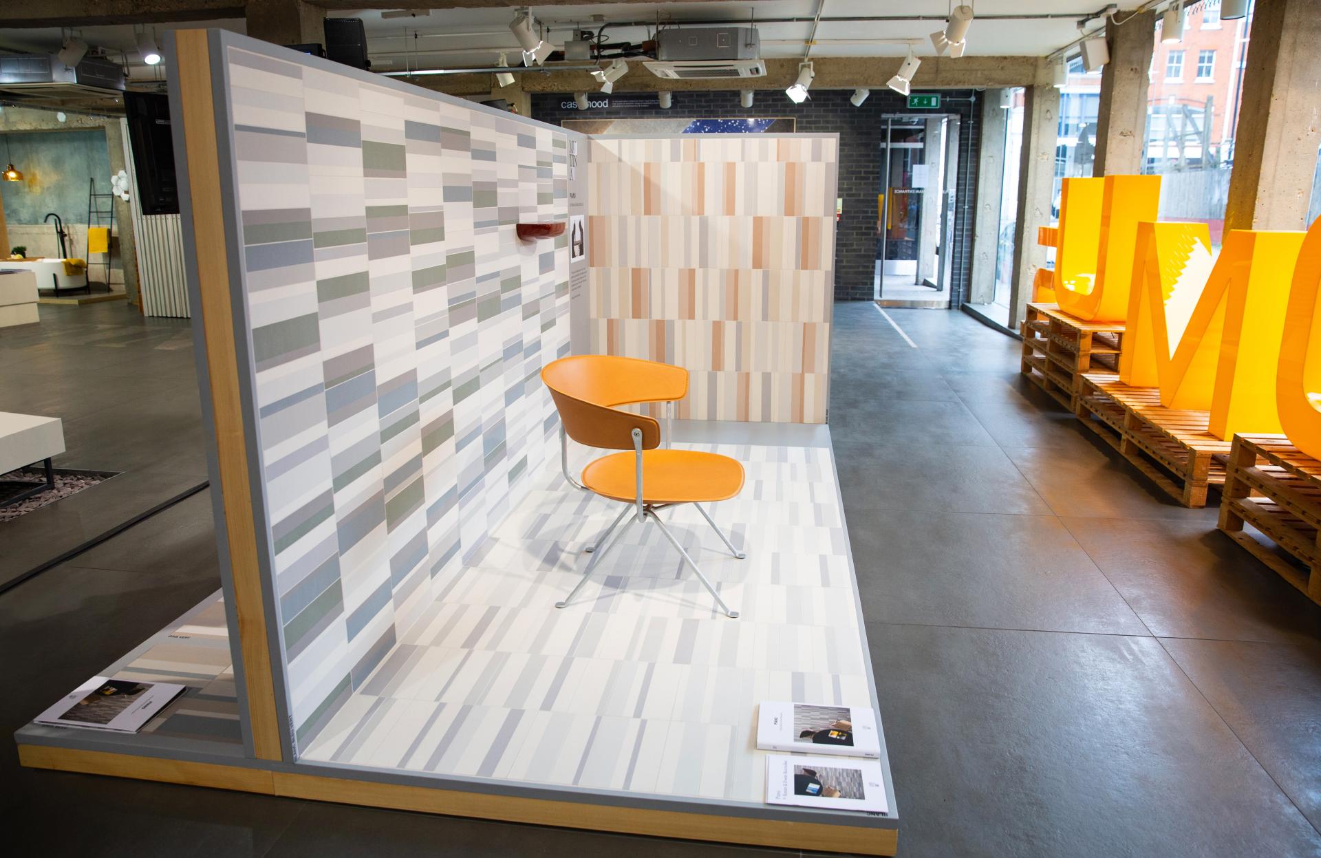 Clerkenwell showroom display featuring a stylish orange chair and modern patterned wall tiles by Domus.