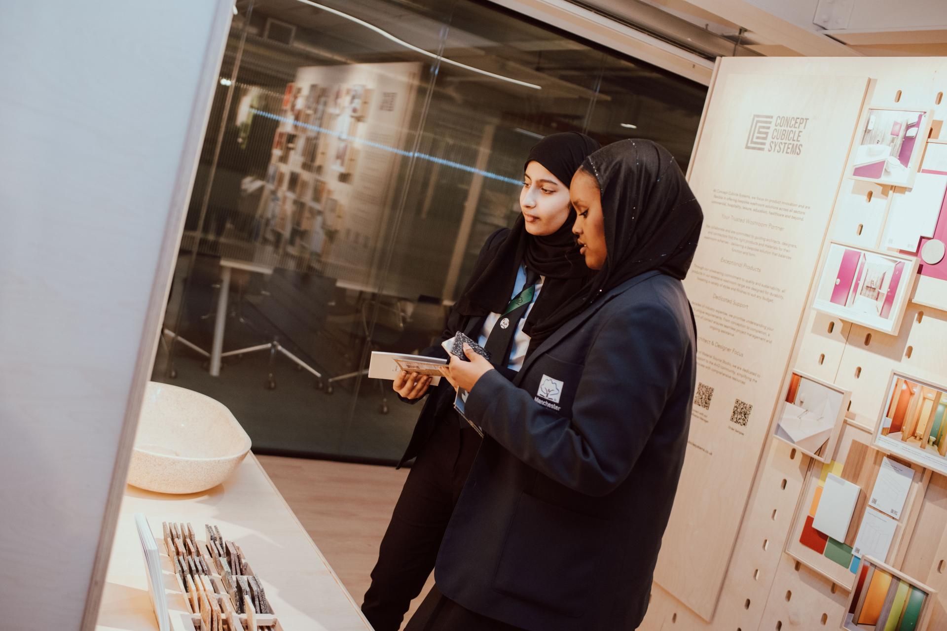 Students engaged in creative collaboration, exploring design materials and samples during a Manchester Academy interior design project.