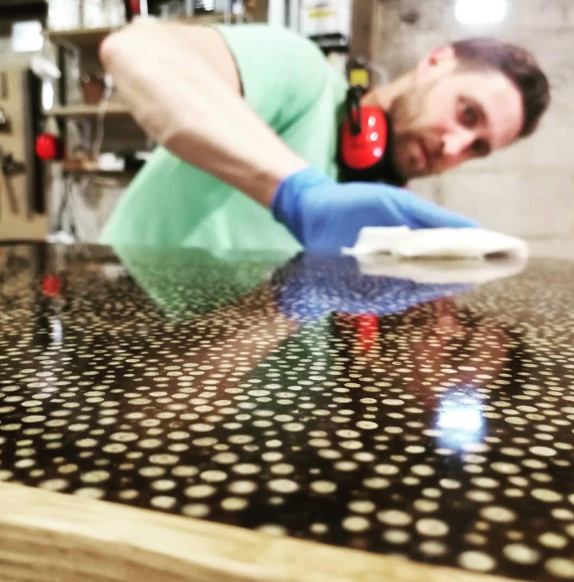 Laurent Peacock refinishing a stunning patterned surface in his workshop, showcasing contemporary furniture design techniques.