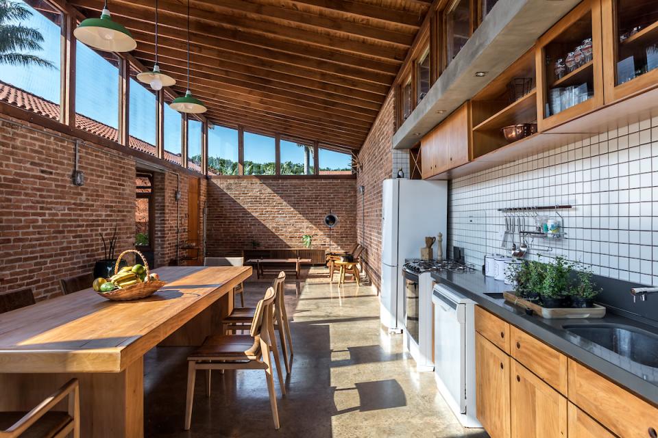 Spacious modern kitchen in The Lake House, featuring natural light, rustic brick walls, and wooden dining furniture.