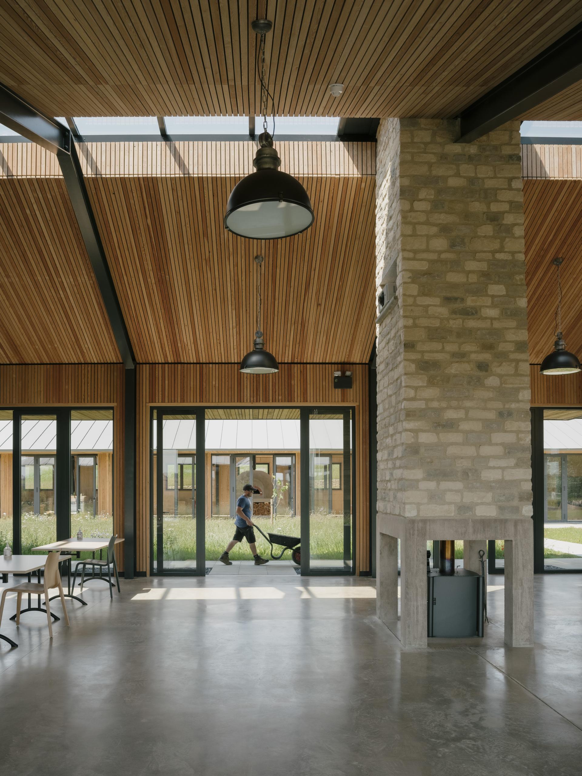 Sustainable farming education centre interior with a person using a wheelbarrow, showcasing contemporary architecture and natural lighting.