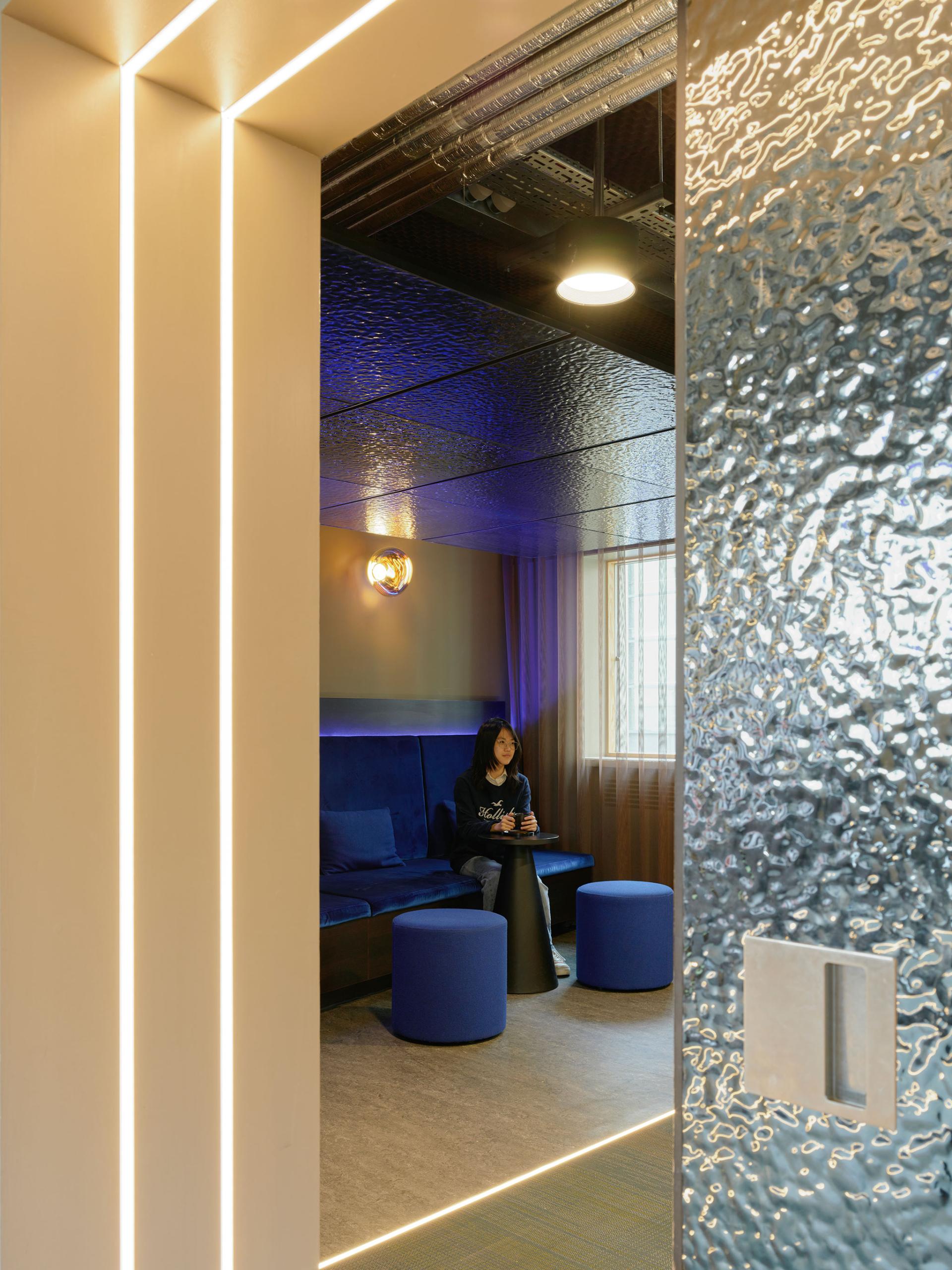 Modern interior space at 16-18 Potterrow featuring atmospheric lighting, lounge seating, and a reflective glass door.