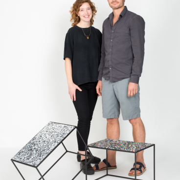 Creative team standing beside hand-crafted panels made from waste materials, showcasing Smile Plastics' sustainable design approach.