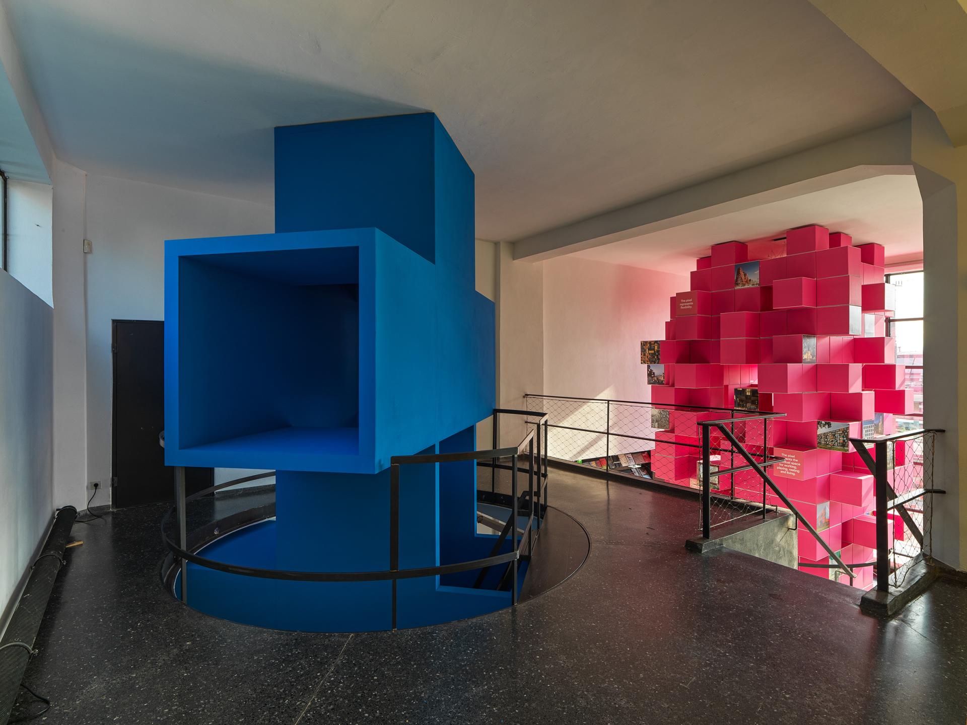 Colorful architectural installation with a blue structure and pink cube display, featured in the Architecture Speaks exhibition by MVRDV.