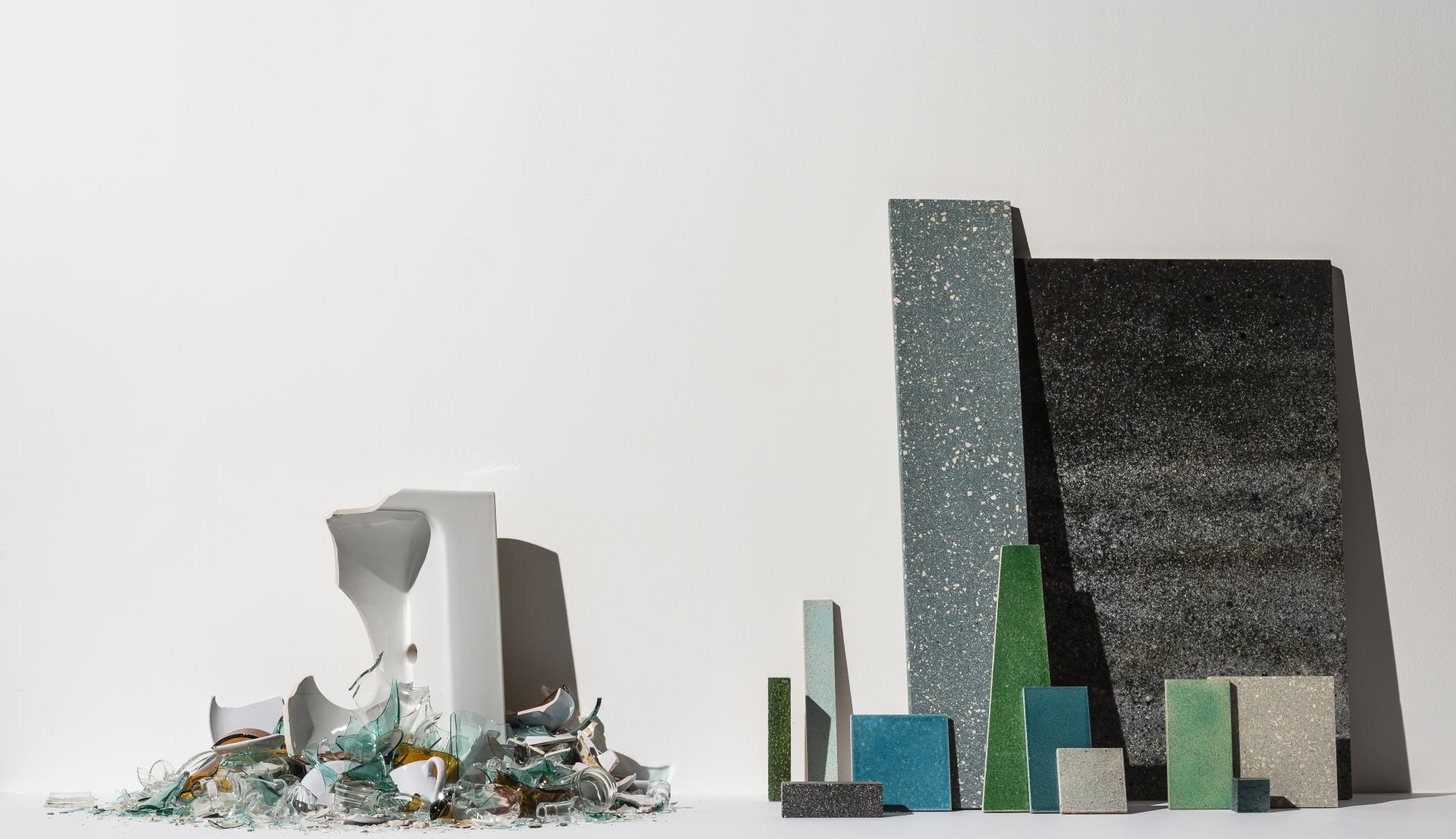 Sustainable material samples displayed with broken ceramics, highlighting innovation in eco-friendly surface design by Alusid.