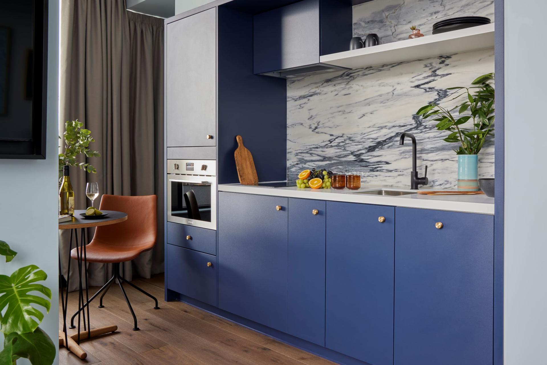 Modern kitchen design featuring Wyndham Oak cabinetry, marble splashback, and stylish dining area in Beckett Locke aparthotel.