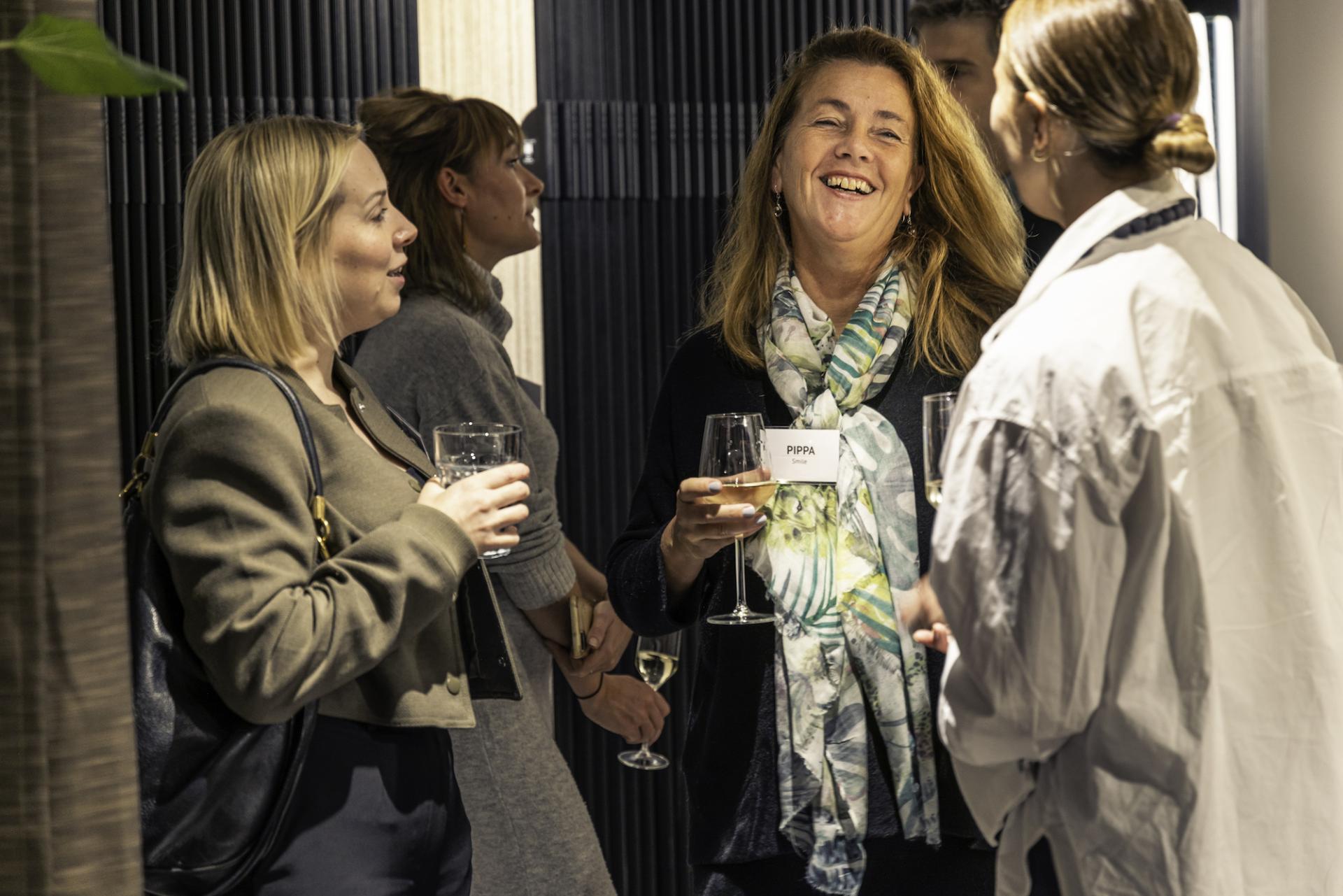 Professionals engaging in discussion at a workplace event, embracing technology and networking in a post-pandemic environment.