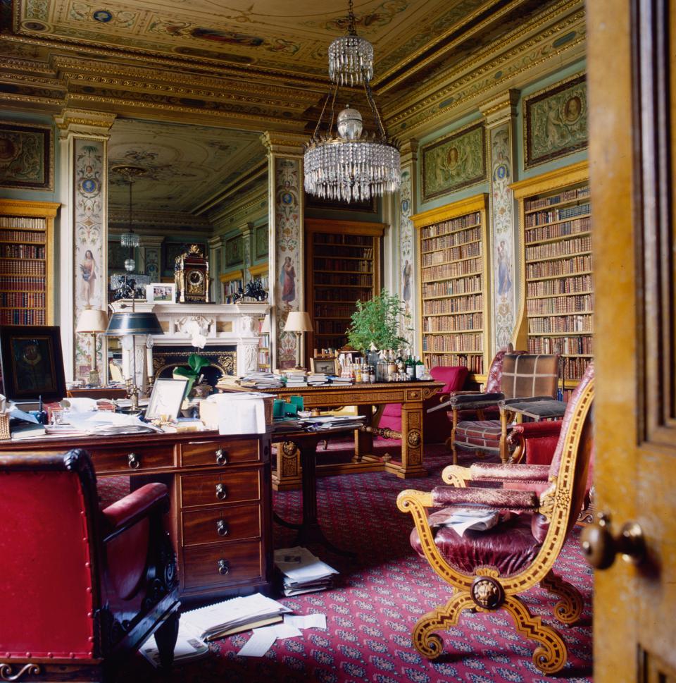 Elegant interior of a historic British library featuring ornate furniture, a grand chandelier, and extensive bookshelves.