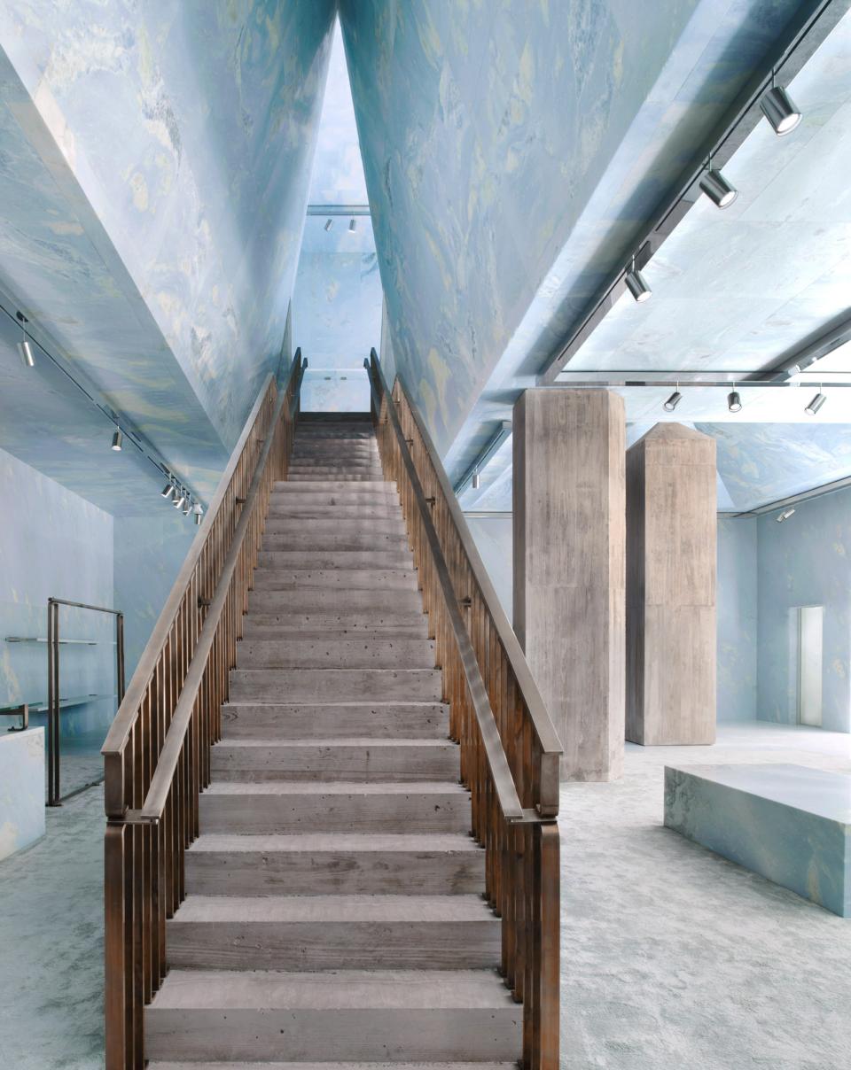 Stunning interior of Céline's Miami store featuring a wooden staircase, blue marble surfaces, and concrete pyramid shapes.