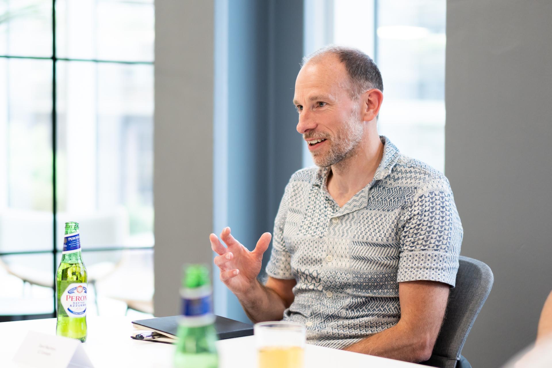 Businessman discussing innovative technology solutions in a modern workspace, surrounded by beverages and a collaborative atmosphere.