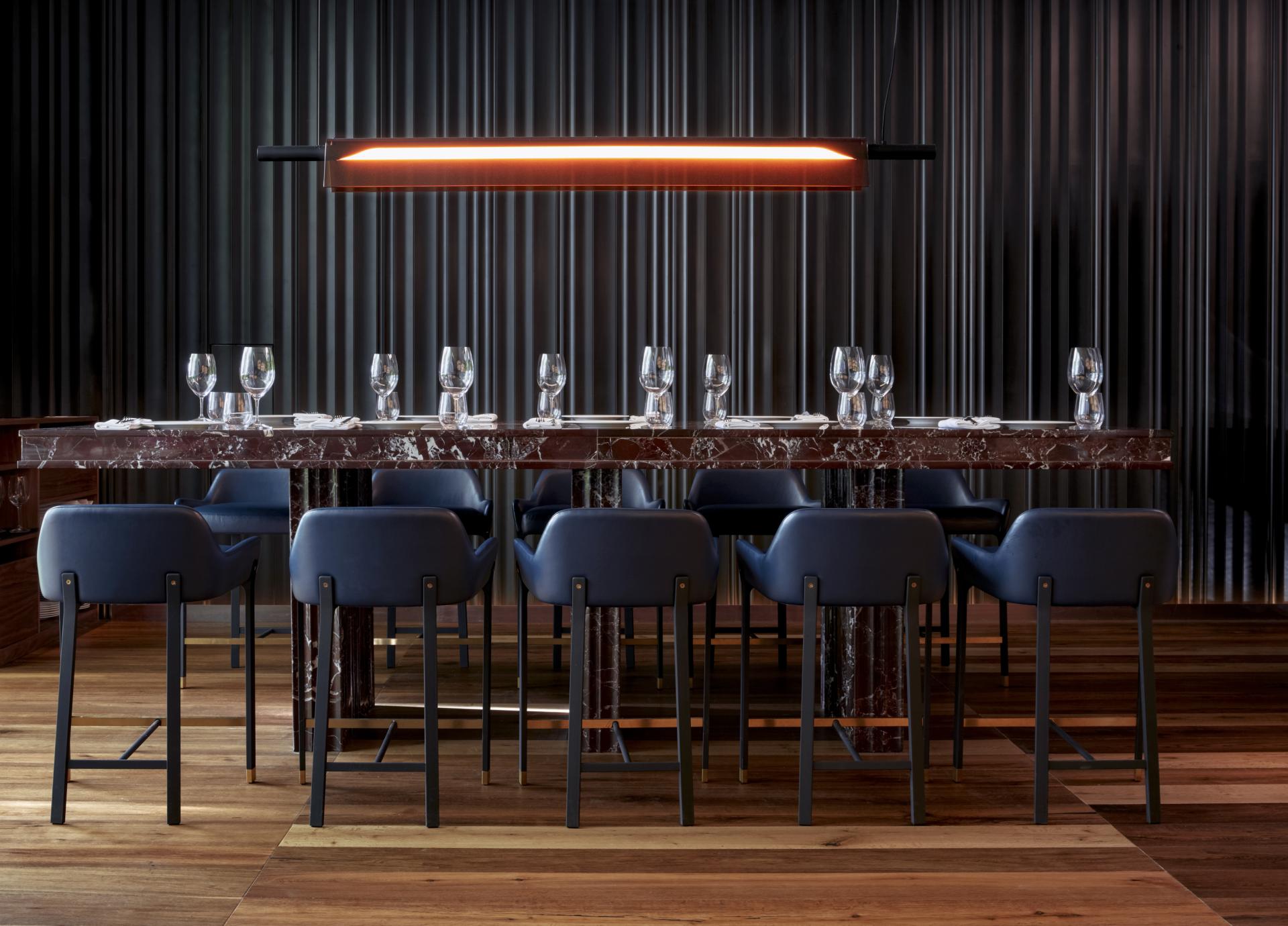 Elegant dining area at Sir Victor hotel, featuring a marble table, stylish chairs, and contemporary lighting design.