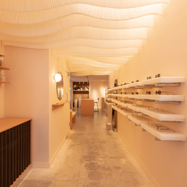 Interior of a modern zero-waste eyewear store featuring stylish frames on wooden shelves and a warm, inviting atmosphere.