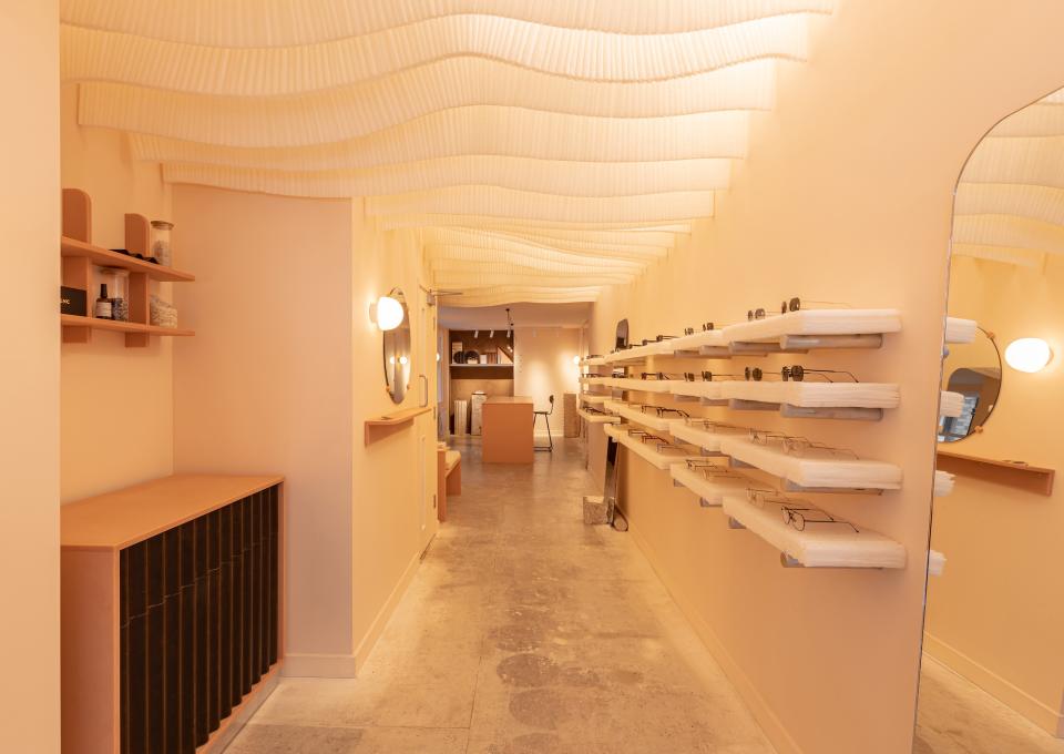 Interior of a modern zero-waste eyewear store featuring stylish frames on wooden shelves and a warm, inviting atmosphere.