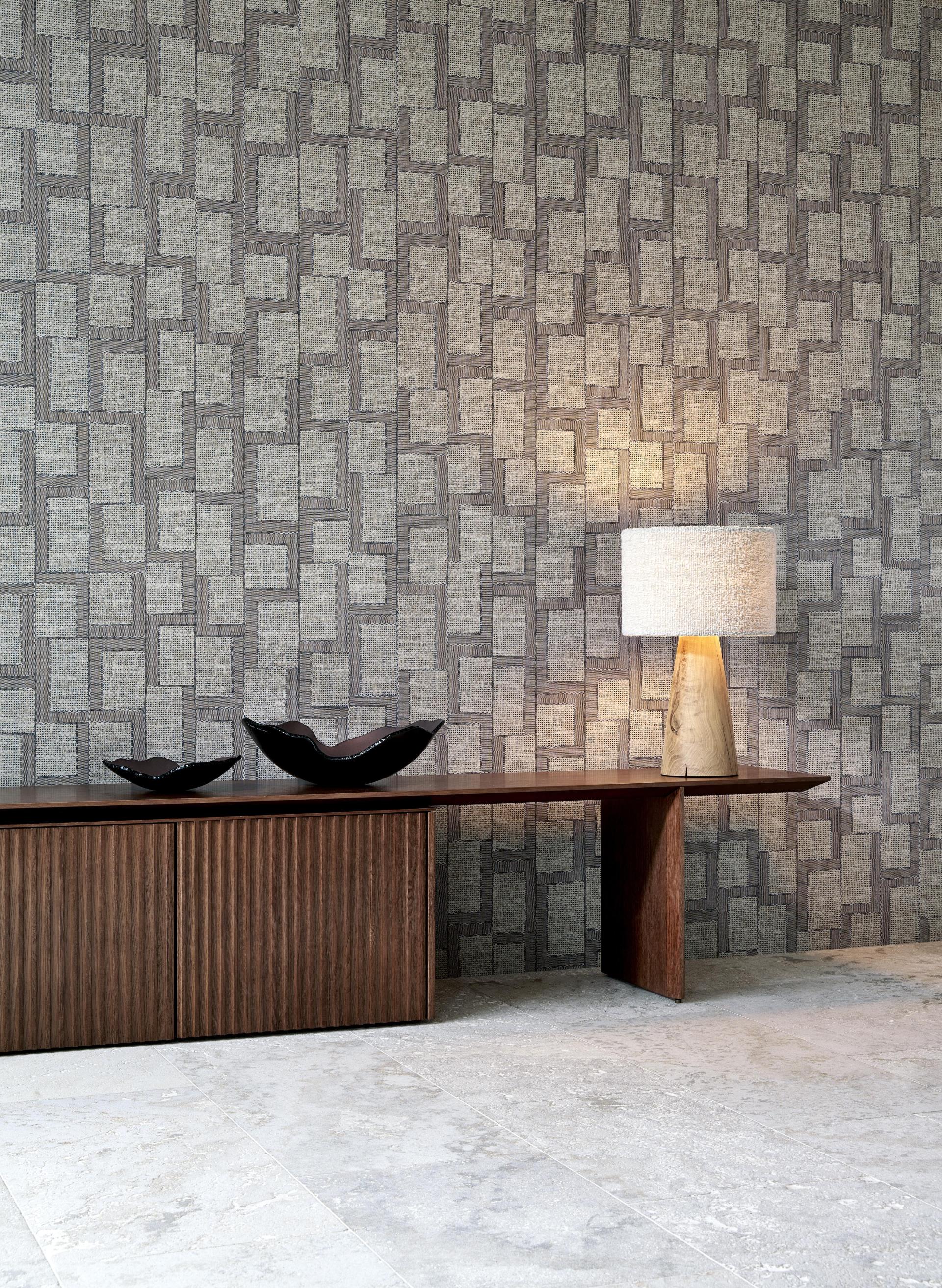 Geometric totem-inspired wallcovering in neutral tones, complemented by a wooden console and decorative bowls.
