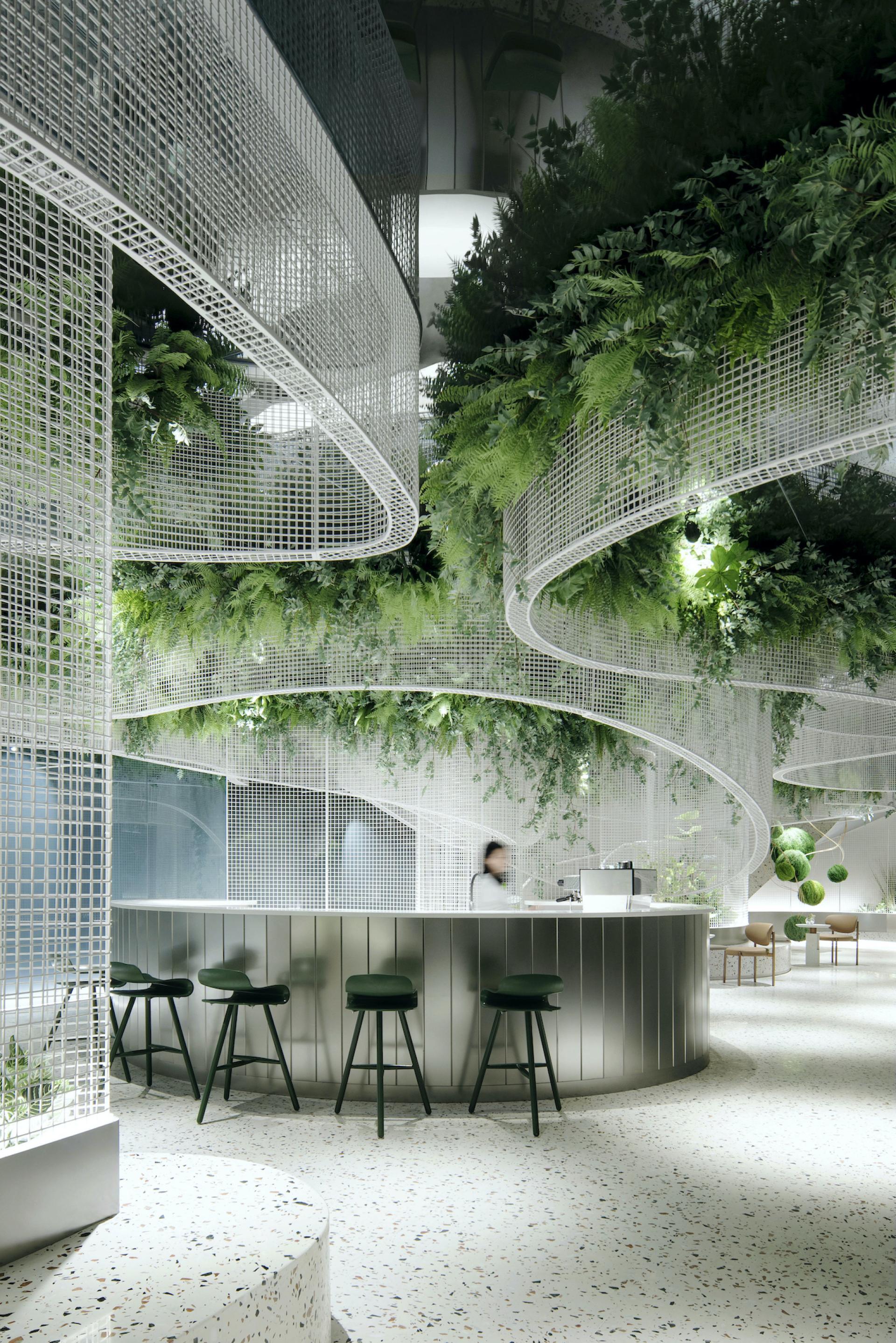 Stylish café interior featuring terrazzo flooring, curved mesh grids, and abundant greenery at Vista by Karv One.