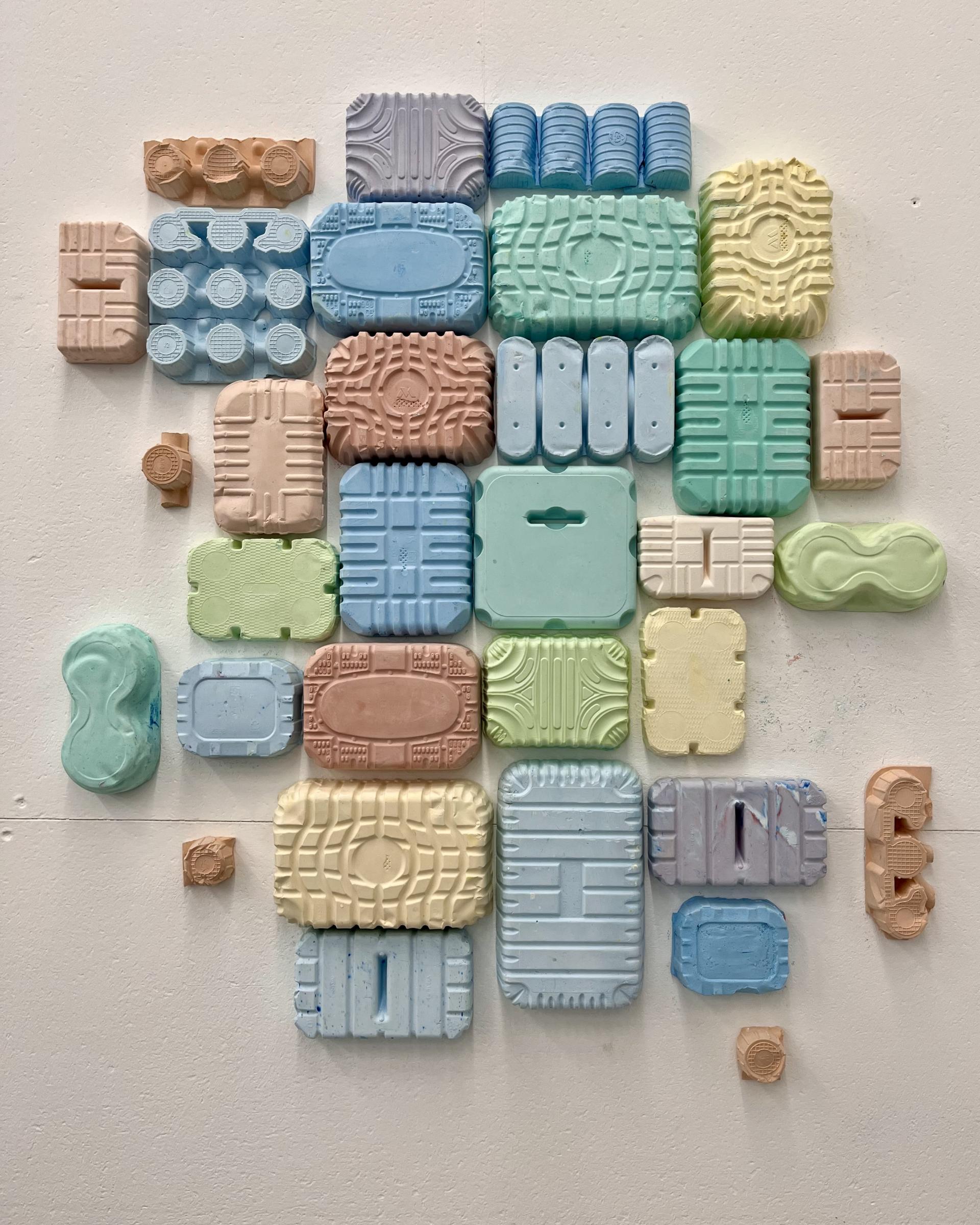 Colorful wall display of creatively reimagined plastic waste forms by May Wild Studio and Hopwood Hall students.