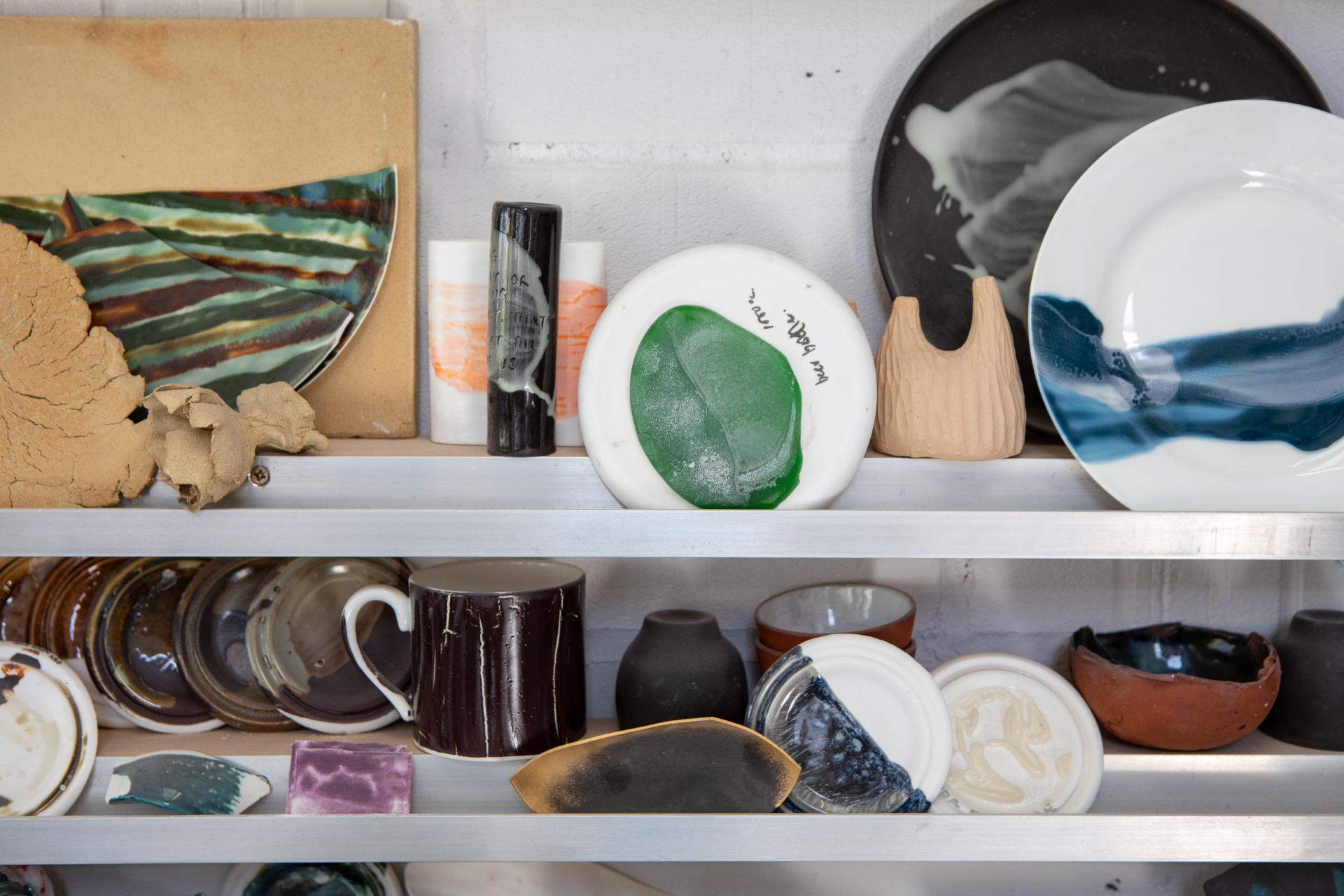 Collection of colorful ceramic pieces, including plates, mugs, and sculptures, showcasing Reiko Kaneko's unique designs.