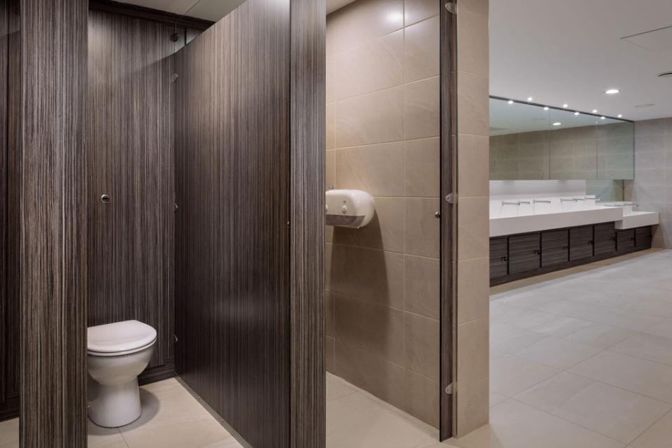 Modern washroom interior at Liverpool Street Station, featuring stylish partitions, a white toilet, and sleek vanities.