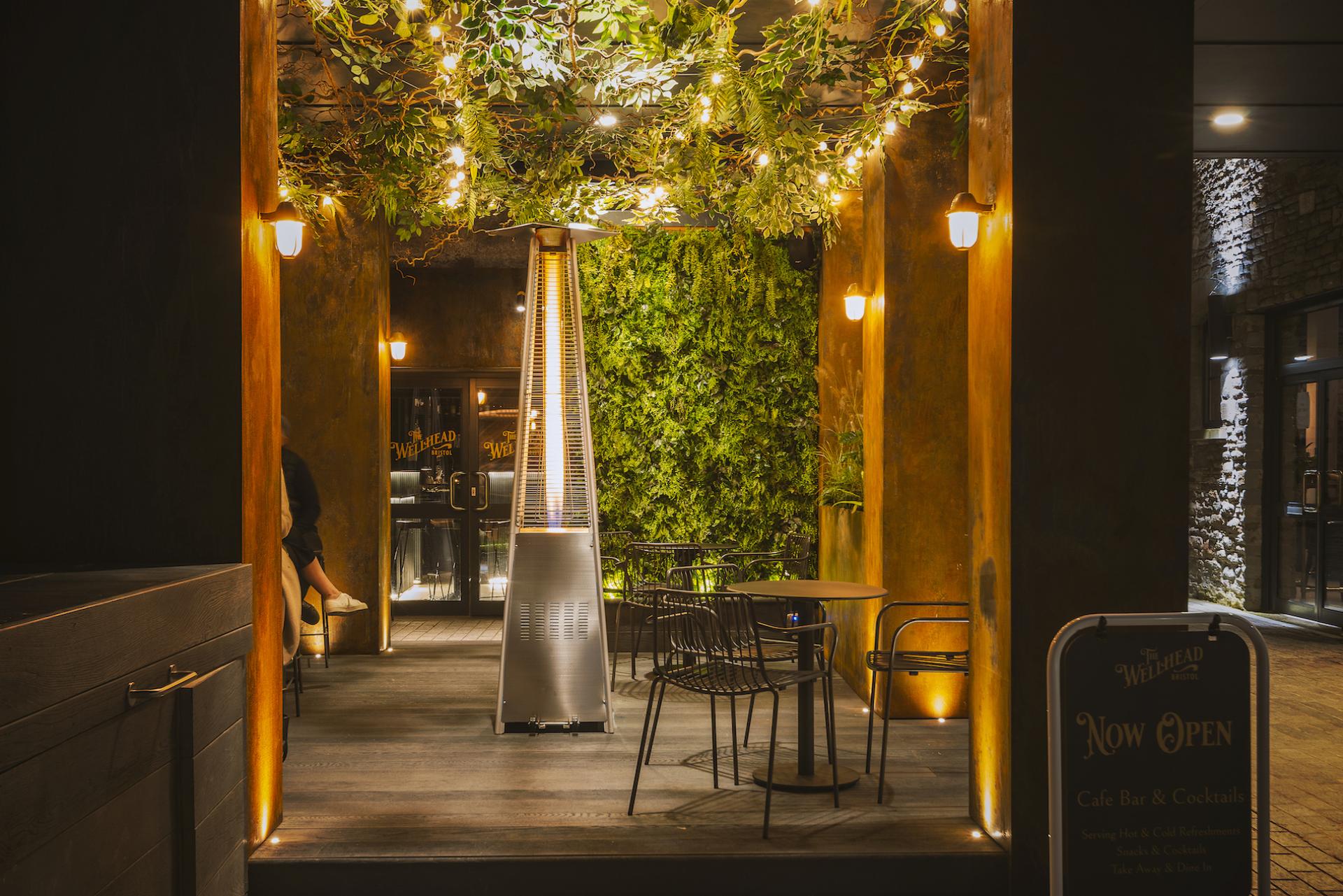 Lush greenery and warm lighting create a cozy atmosphere at The Wellhead, a new coffee and cocktail bar in Bristol.