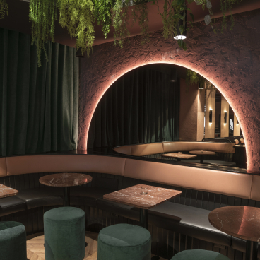 Tropical-themed restaurant interior featuring plush seating, marble tables, and lush greenery in Montreal's transformed auto repair shop.