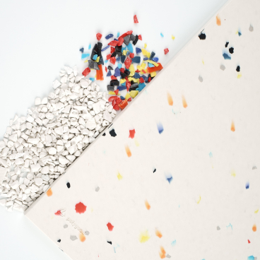 Recycled plastic materials and colorful chips next to a solid surface sheet, showcasing sustainable design innovations by CDUK.