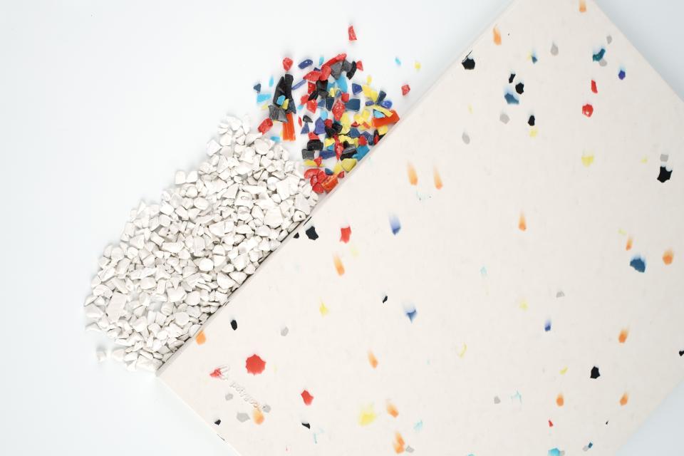 Recycled plastic materials and colorful chips next to a solid surface sheet, showcasing sustainable design innovations by CDUK.
