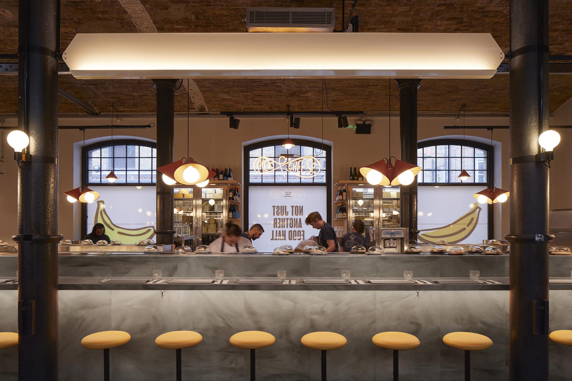 Modern restaurant interior featuring a sleek countertop, yellow stools, and decorative lighting, highlighting the new Corian color range.
