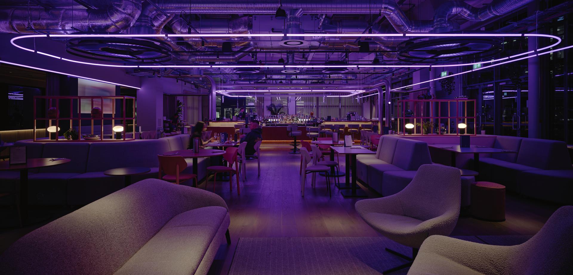 Modern interior of Junction at Manchester Central featuring vibrant purple lighting and contemporary seating arrangements.