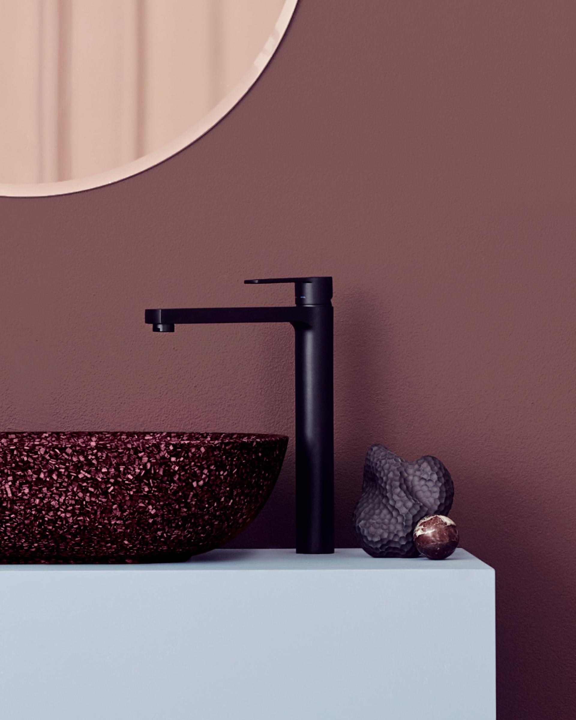 Stylish low-carbon washroom featuring a black faucet and a textured burgundy sink against a muted backdrop.