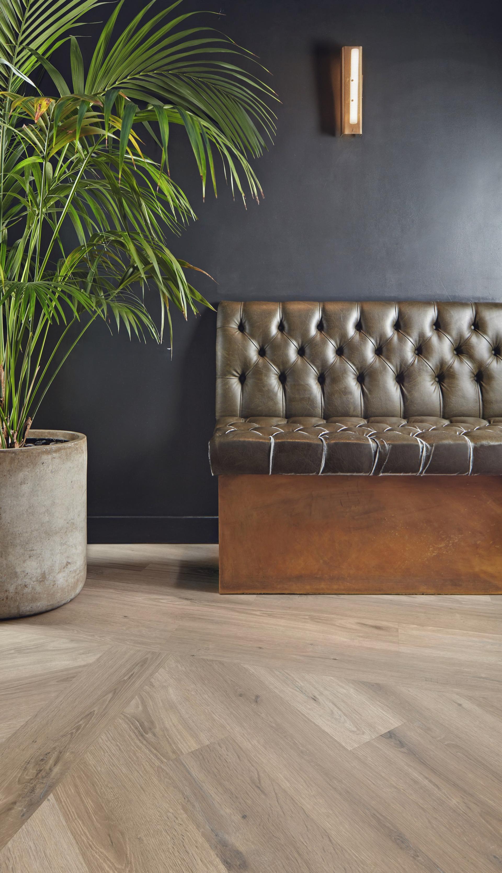 Stylish contemporary interior featuring Karndean Knight Tile flooring, a vintage tufted leather bench, and lush greenery.