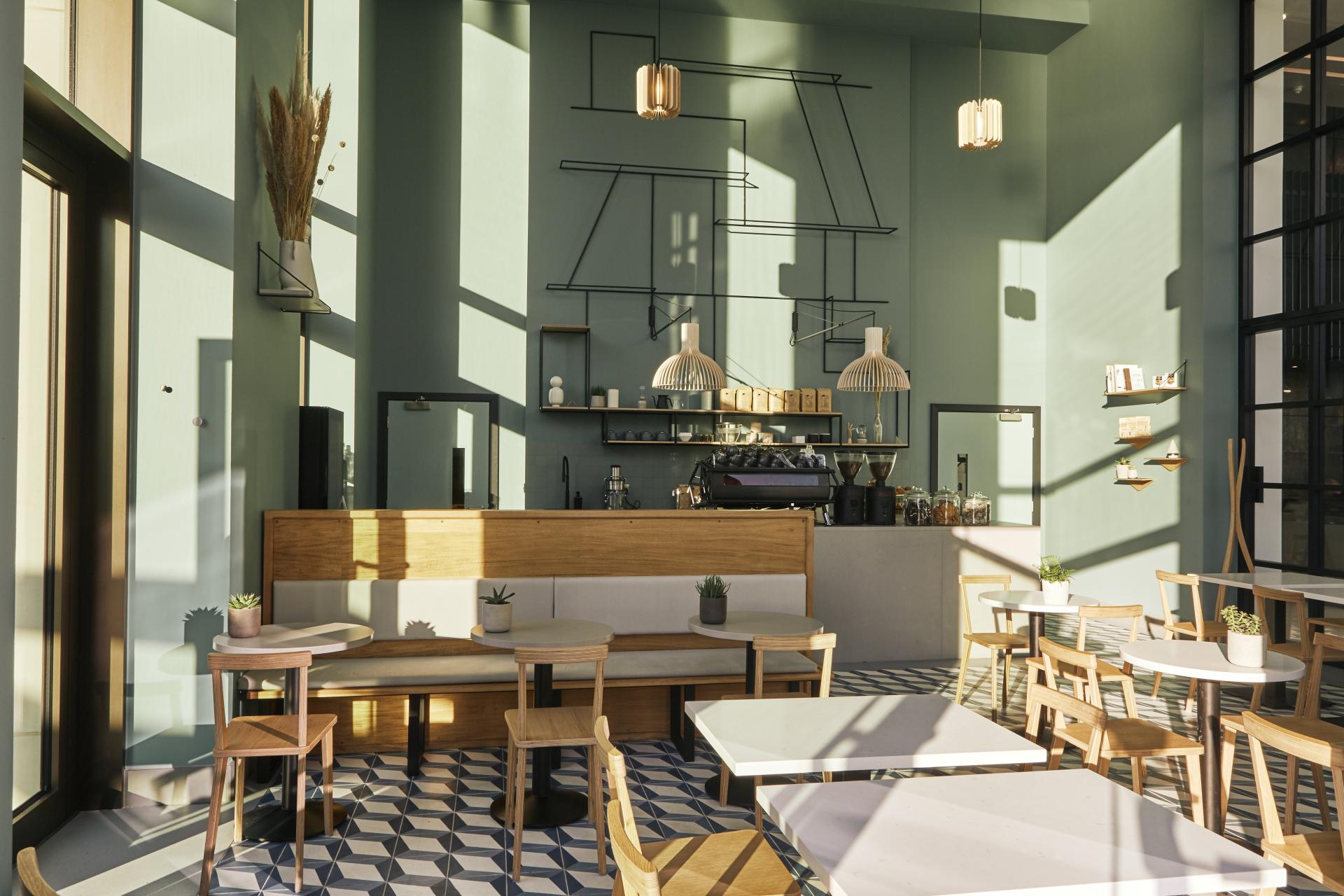 Stylish café interior featuring Caesarstone Raw Concrete and Misty Carrera surfaces, with modern seating and artistic decor.