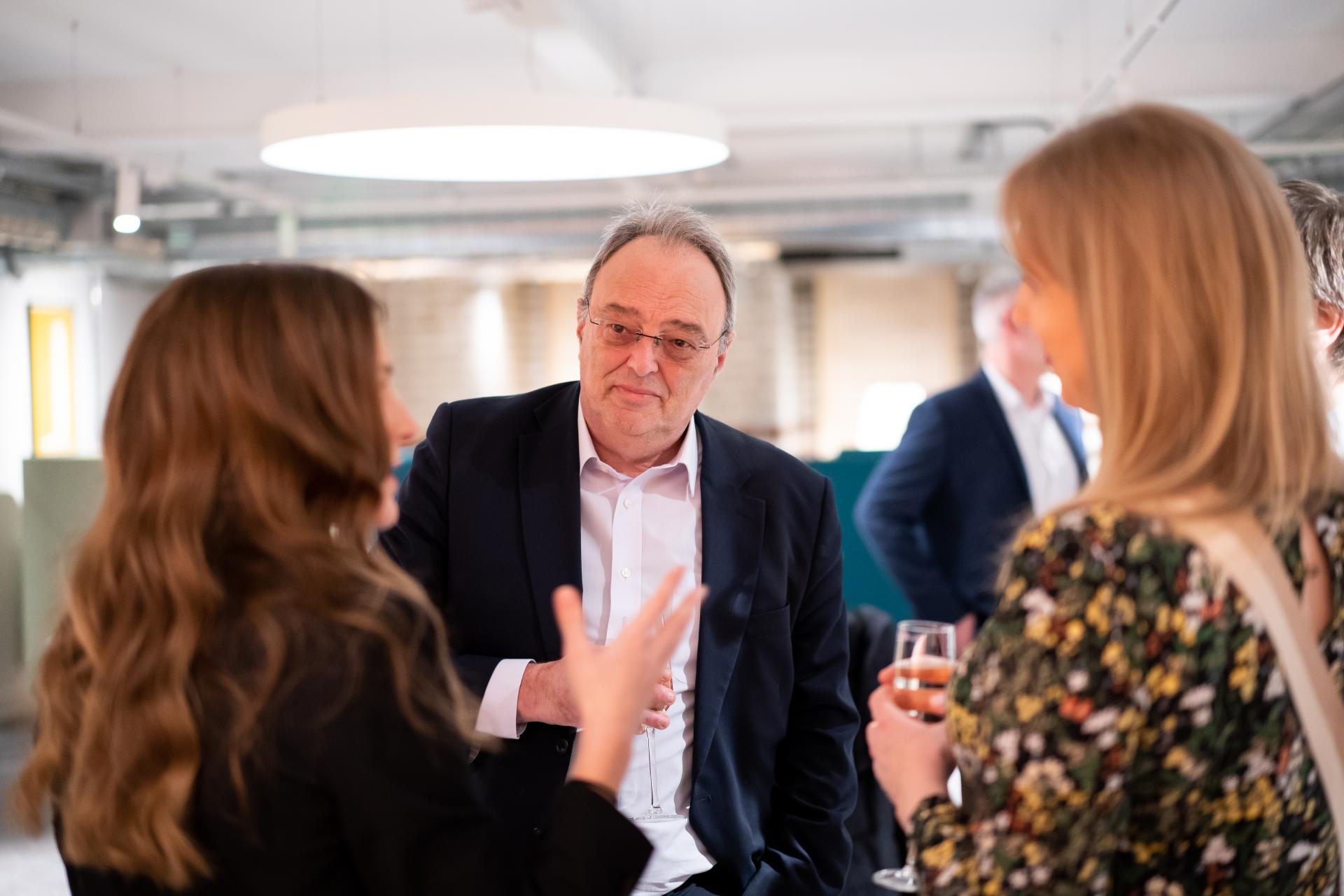 Three professionals engage in discussion at a sustainability seminar, highlighting themes of collaboration and responsibility.