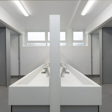 Modern boys’ washroom at Stretford Grammar featuring inclusive design, sleek sinks, and private cubicles for accessibility.
