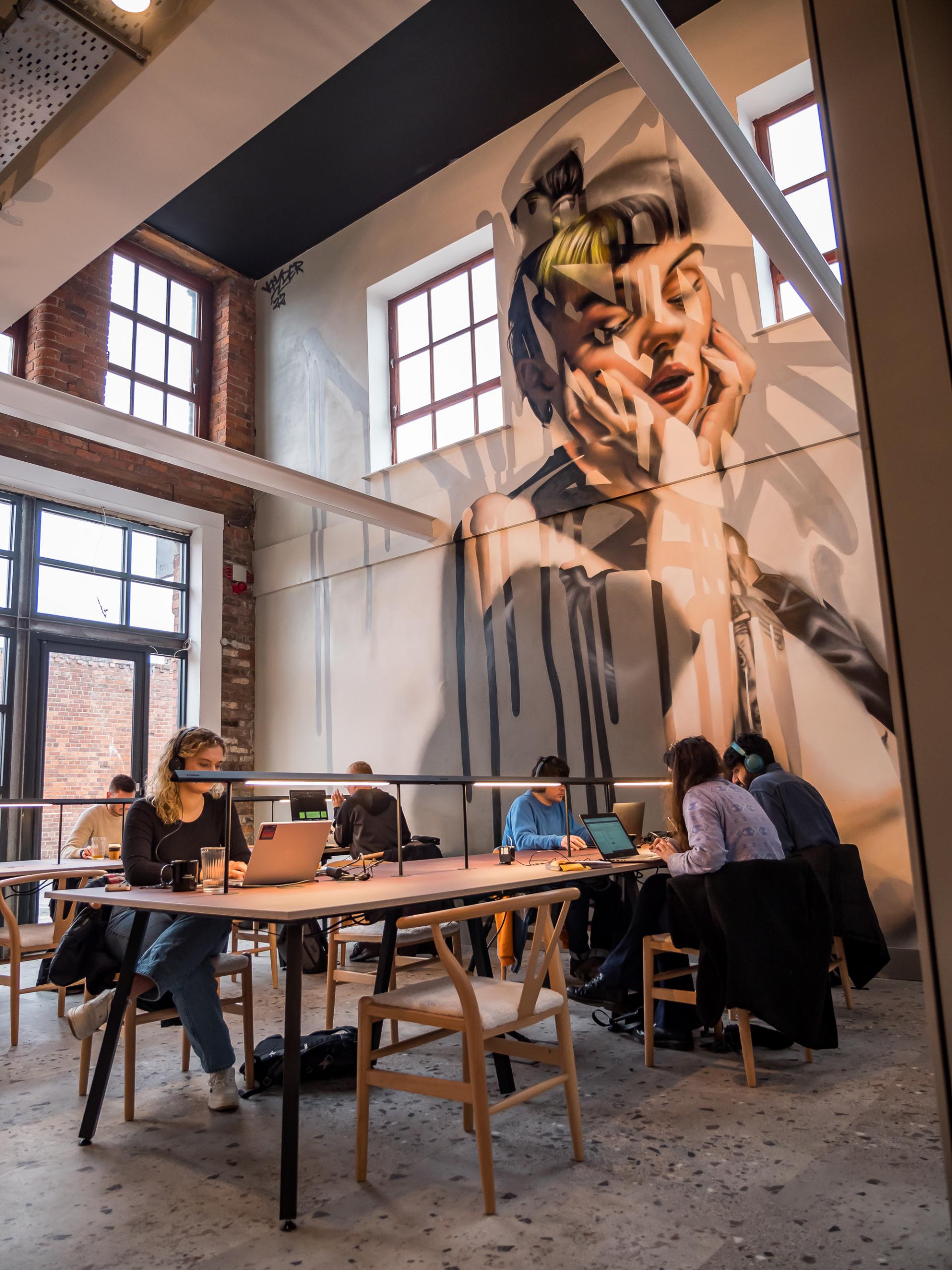 Creative workspace at Colony CoWork featuring a vibrant mural and professionals enjoying a premium coffee experience.