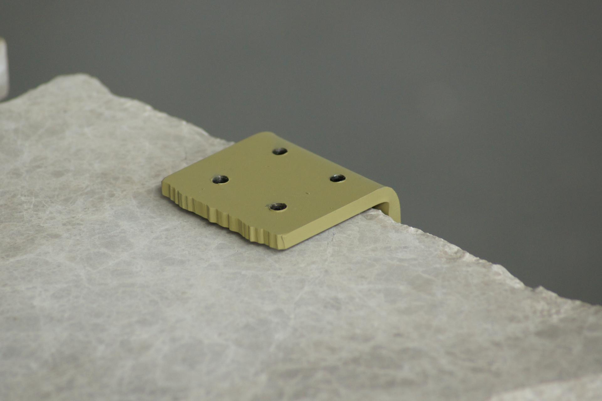 Modern olive green metal hardware resting on a textured light stone surface, highlighting innovative Dutch design craftsmanship.