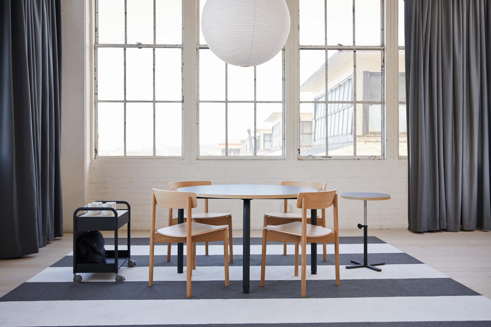 Stylish Routes furniture collection featuring a round table and wooden chairs in a bright, modern workspace.