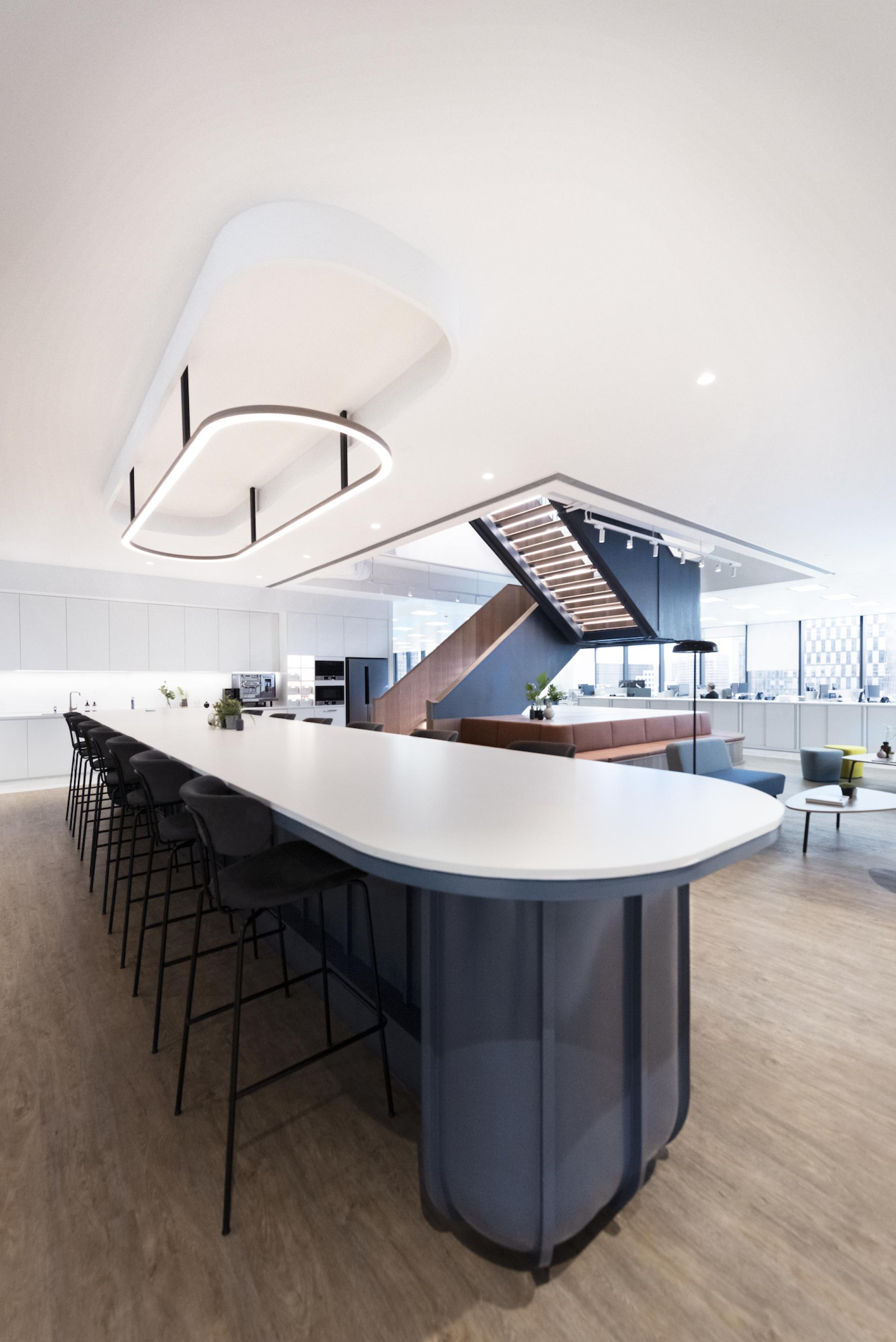 Modern office interior featuring a sleek kitchen island and a stylish staircase, designed by Bean Buro for innovative workspaces.