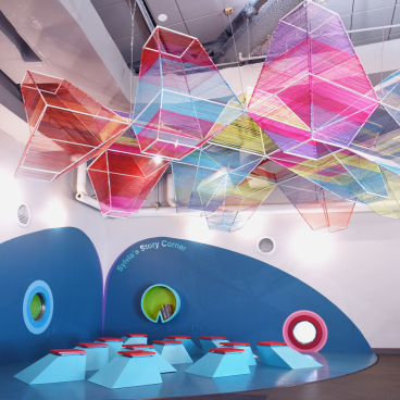 ColorLab's vibrant art space features colorful hanging sculptures above geometric seating for children in Brooklyn.