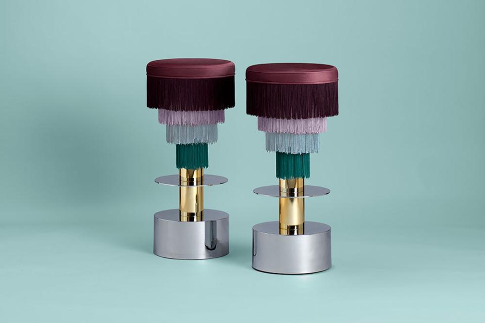 Stylish Déjà Vu stools designed by Masquespacio, featuring vibrant colors and luxurious fringe details against a mint background.