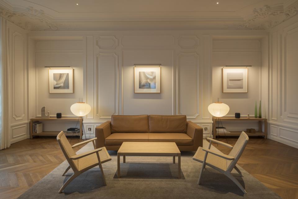 Elegant Parisian apartment interior featuring a leather sofa, modern chairs, and artistic lighting, designed by Foster + Partners.