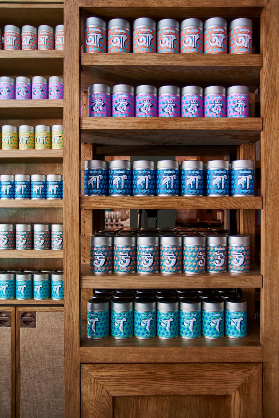 Colorful tea canisters arranged neatly on wooden shelves in Teatulia’s stylish art deco tea shop.