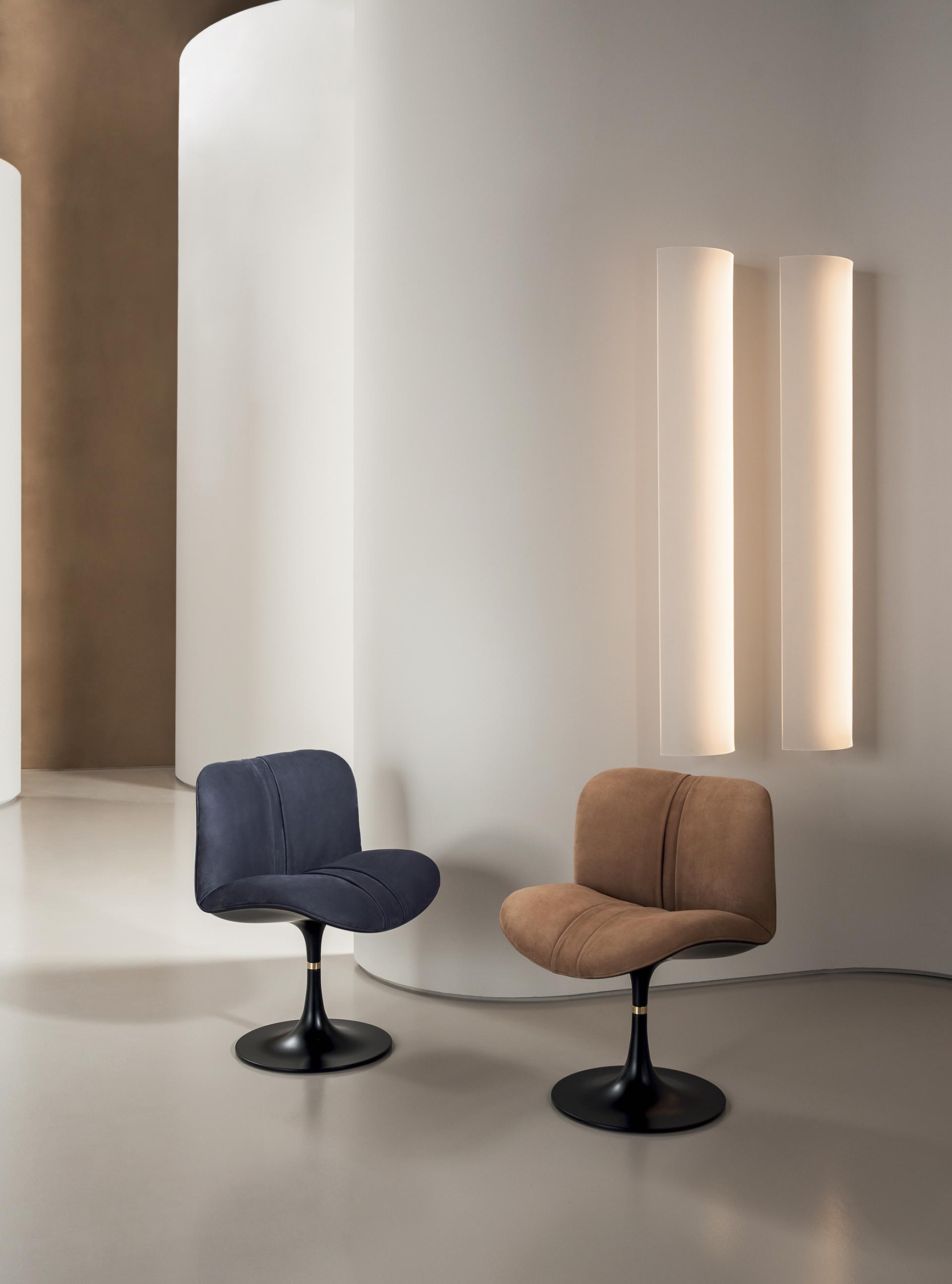 Two contemporary luxury chairs in navy blue and brown fabrics, showcased in a modern interior with elegant lighting.